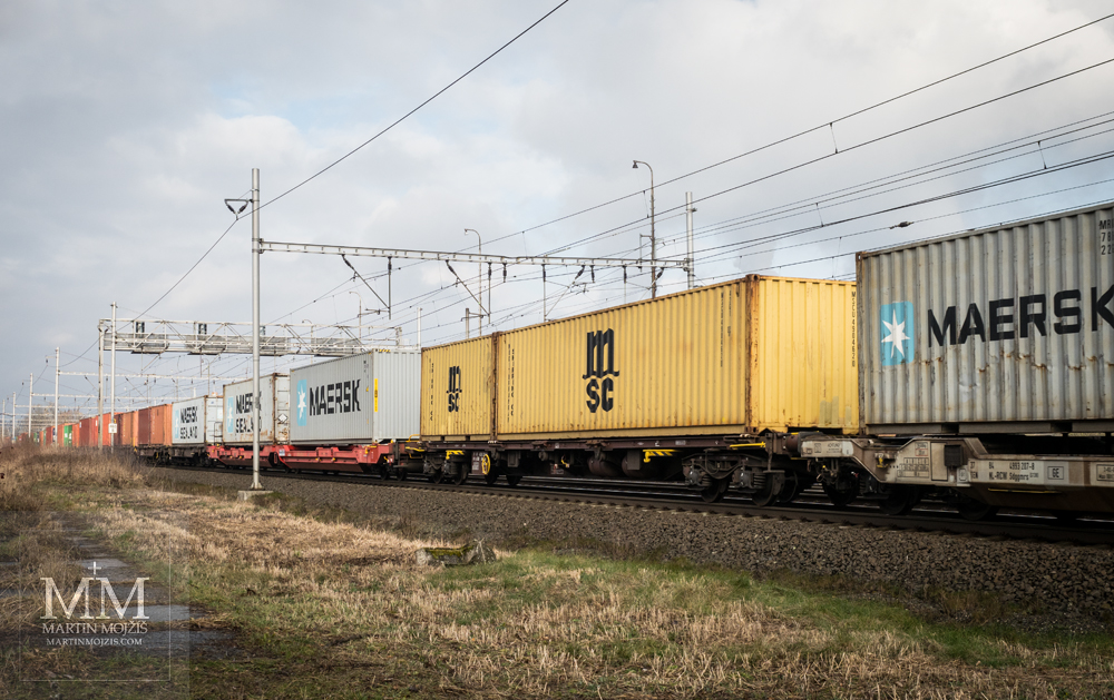 Nákladní vlak přepravující kontejnery. Fotografie vytvořena objektivem Olympus 12 - 40 mm 2.8 Pro.
